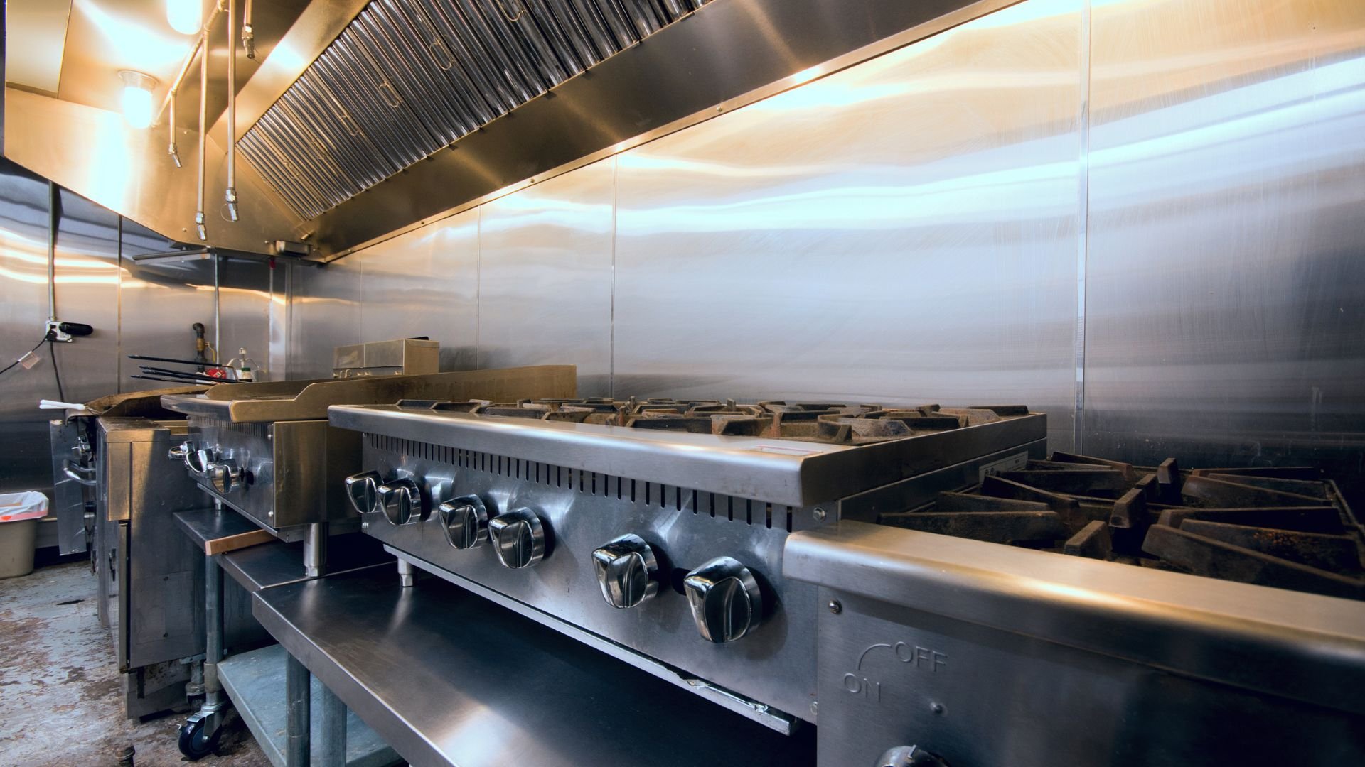 Professional commercial kitchen with stainless steel stove and ventilation hood
