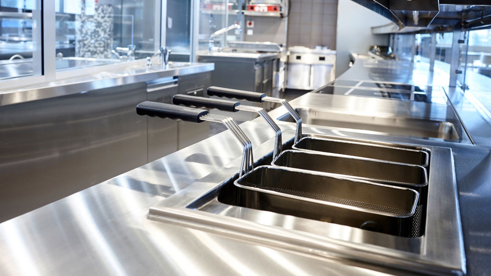 Stainless steel commercial kitchen with frying baskets and clean equipment