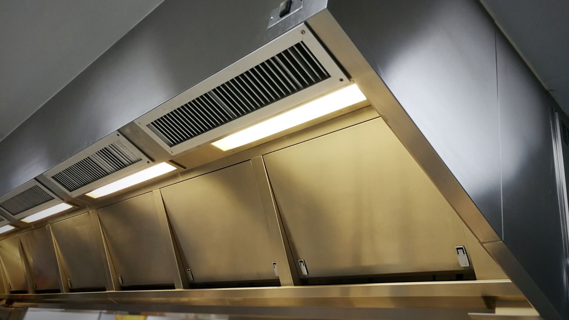 Commercial kitchen exhaust hood with ventilation grilles and lighting