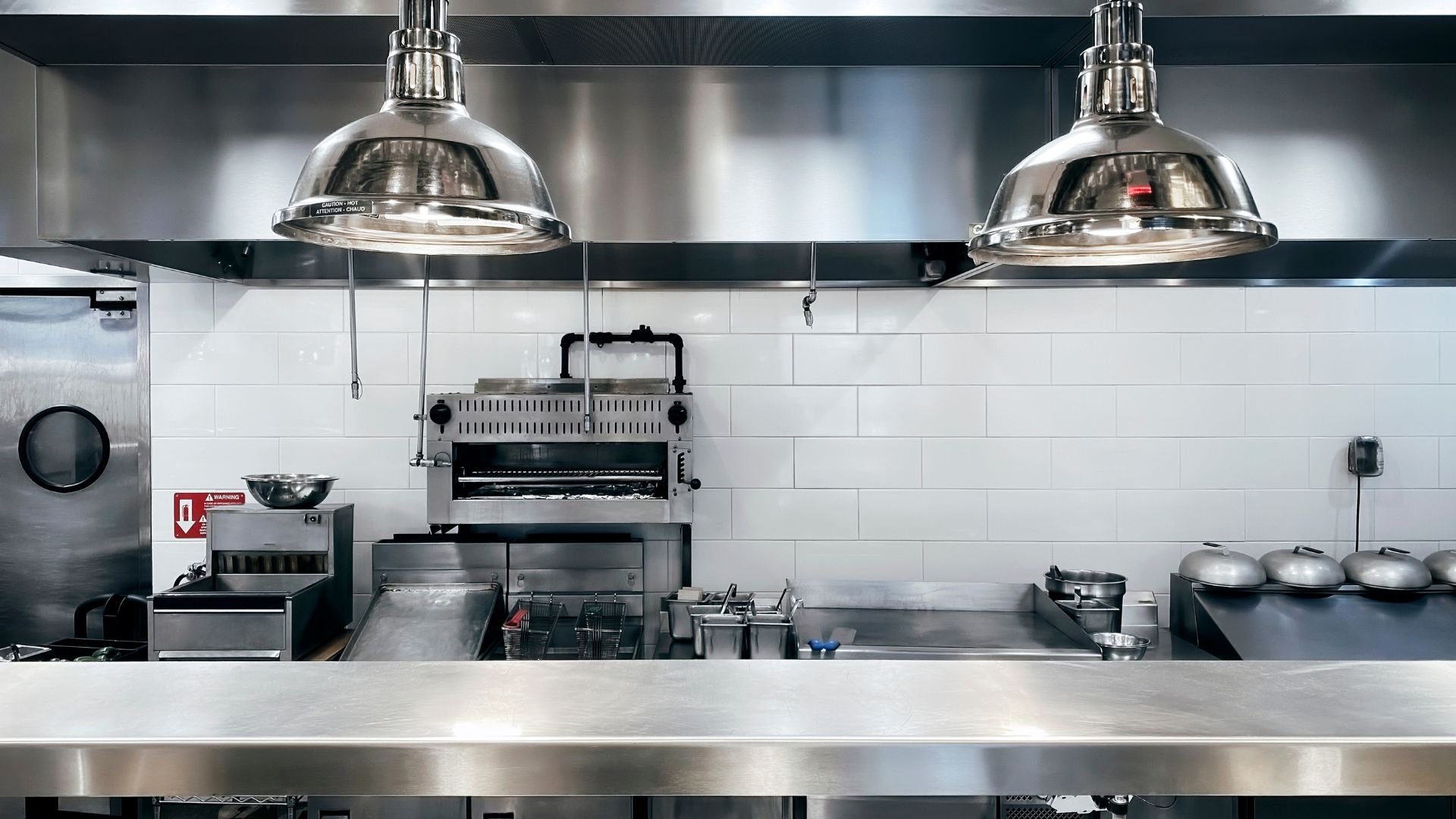 Stainless steel commercial kitchen with industrial lamps and cooking equipment